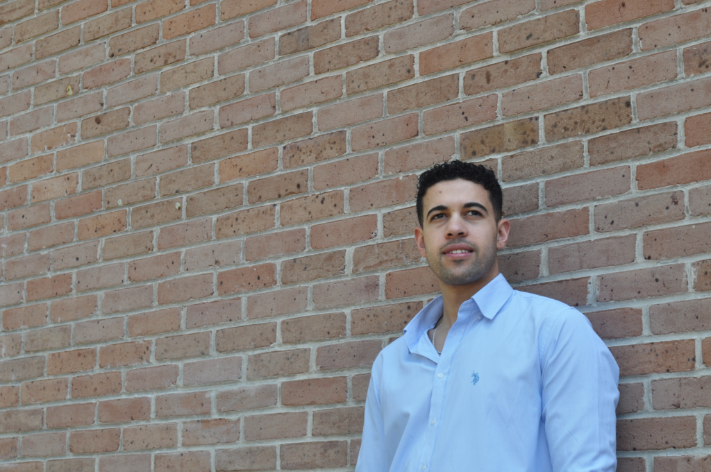 Mahmoud Zaqout poses against a brick wall.